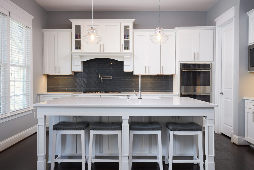 The image is a cover illustration for the real estate referrals page. It shows a beautiful staged kitchen with clear  counters and perfectly placed bar stools which demonstrate the added function of the kitchen island.
